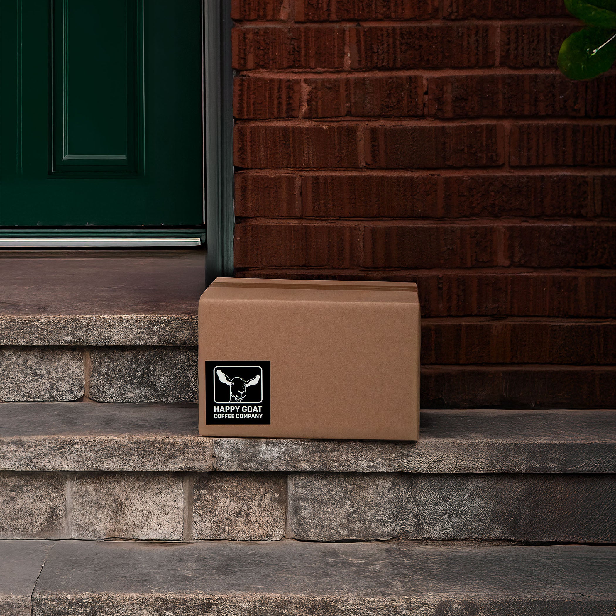 Brown coffee box with a logo on a stone step in front of a green door.