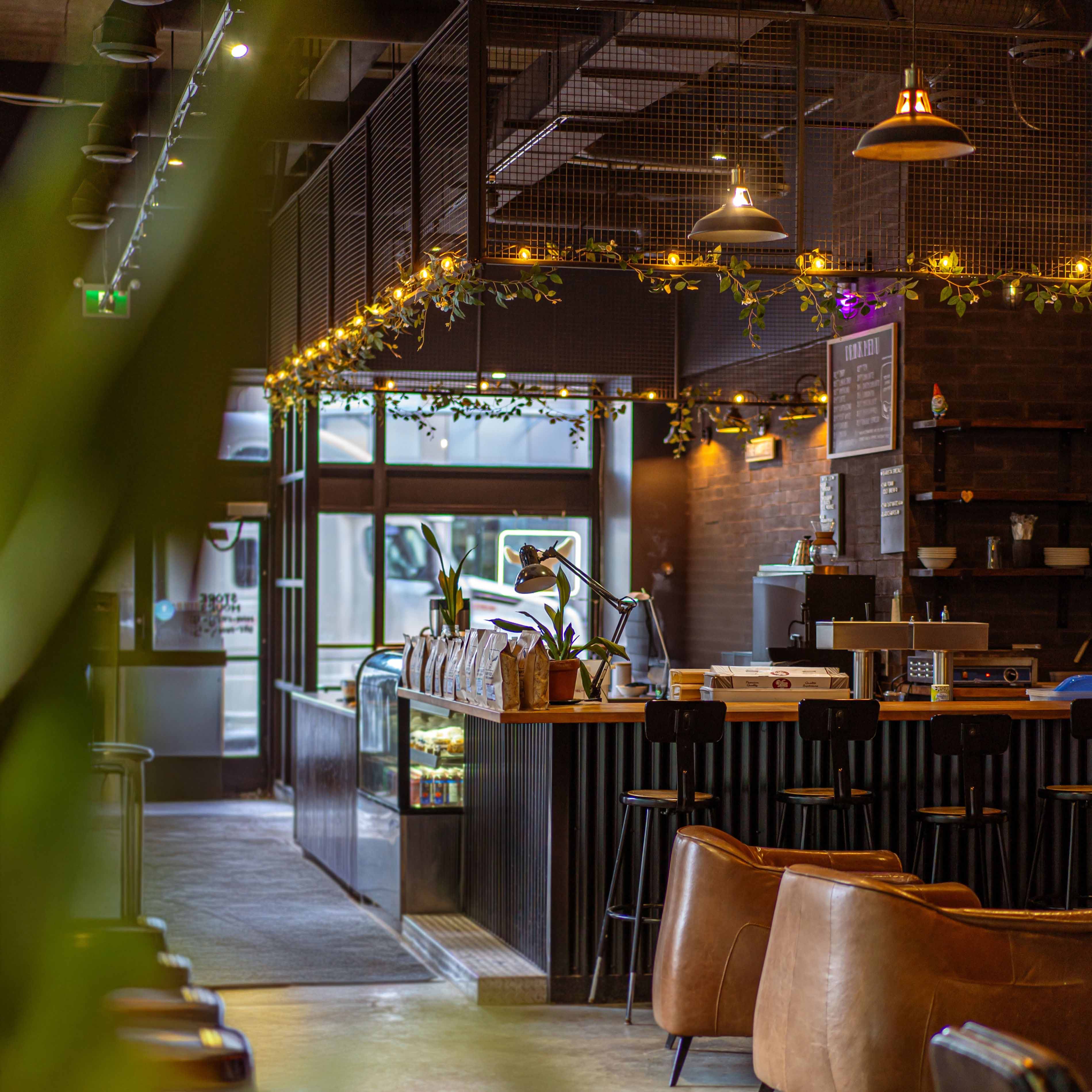 Modern happy goat cafe interior with wooden tables, chairs, and decorative lights.