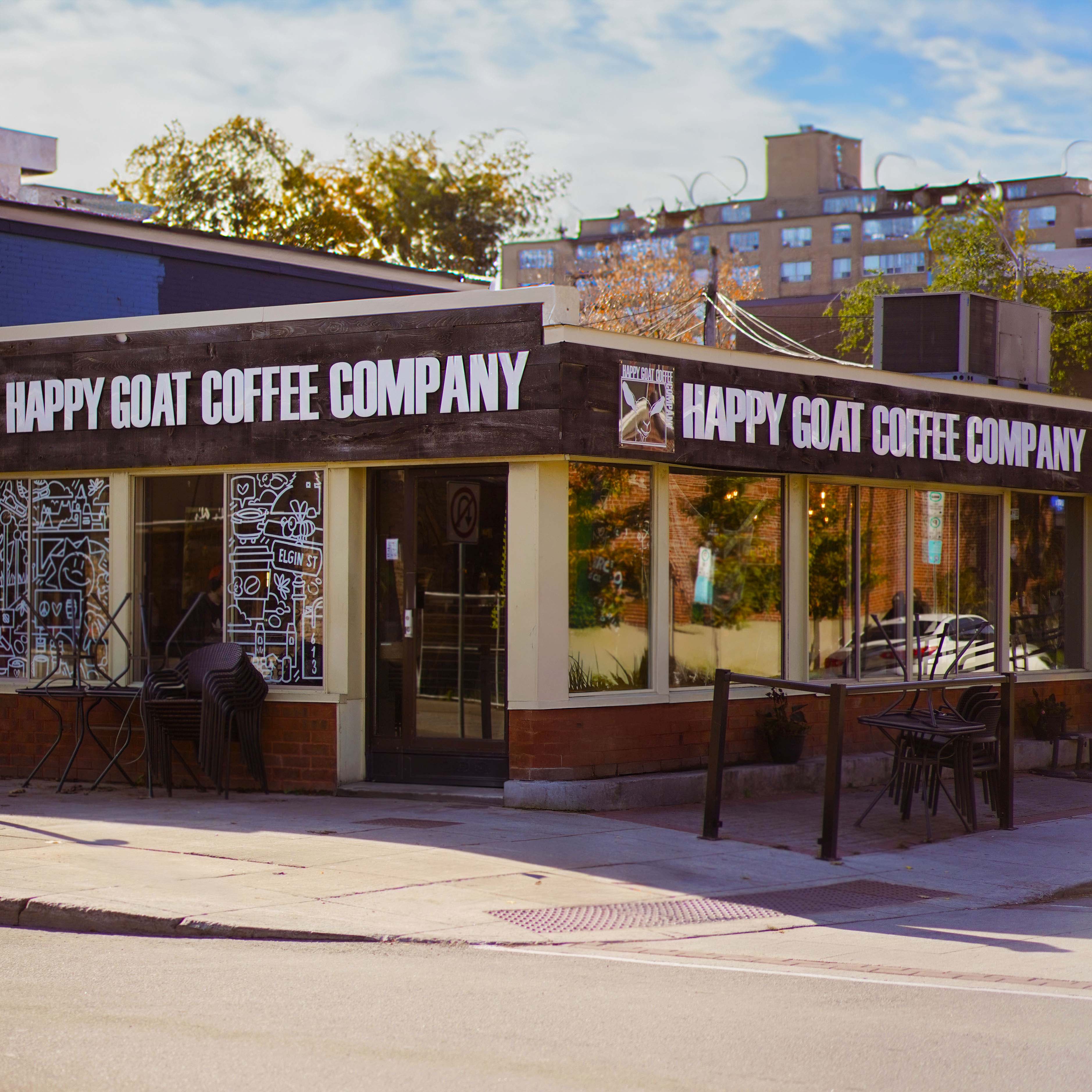 Happy Goat Coffee Company storefront with outdoor seating area on a sunny day.